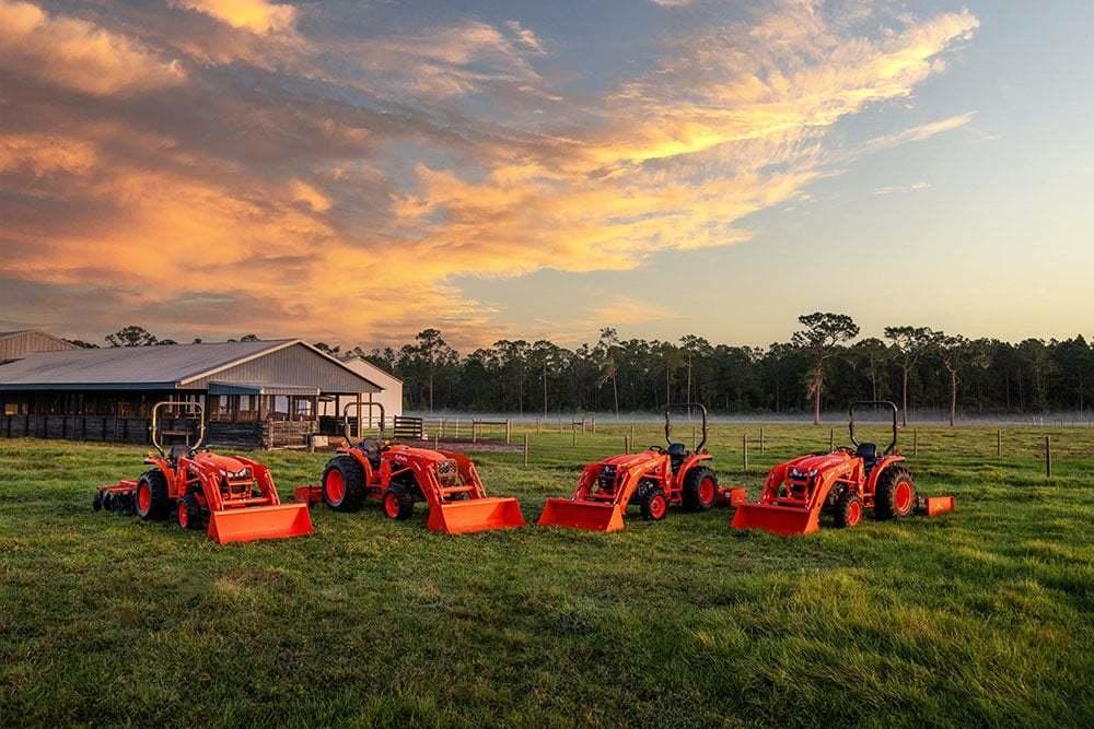 Tractors lined up on a field against a scenic view