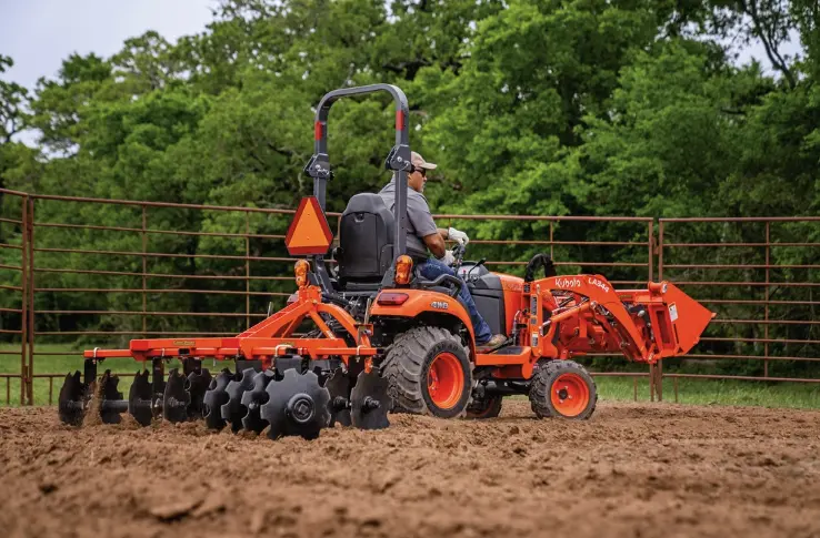 Man plowing field with rear attachment