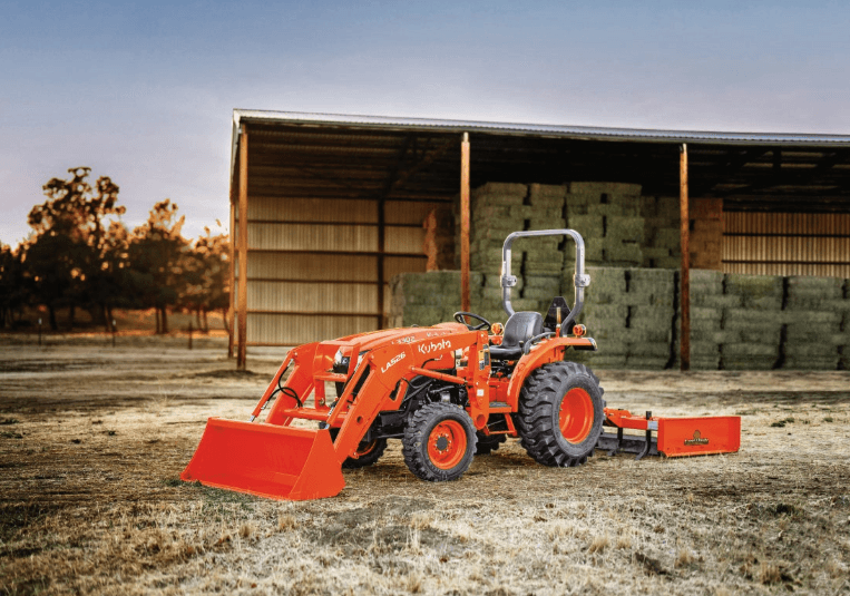 Tractor staged in front of a large shed of hay