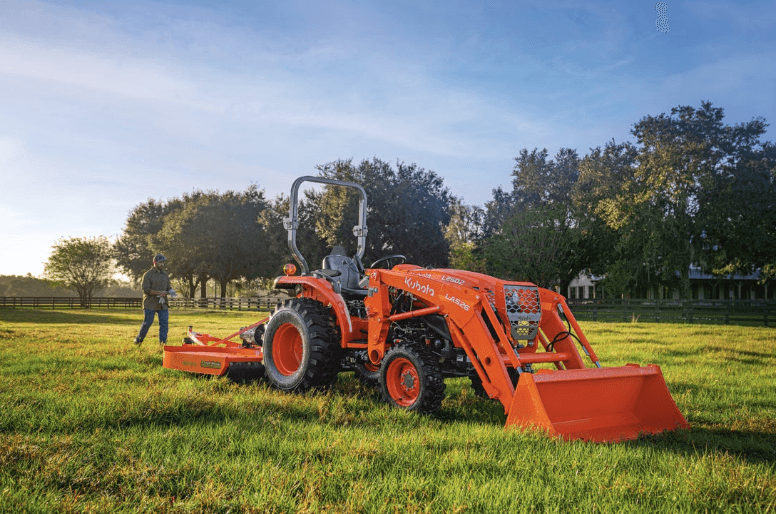 Man walking behind tractor in a field