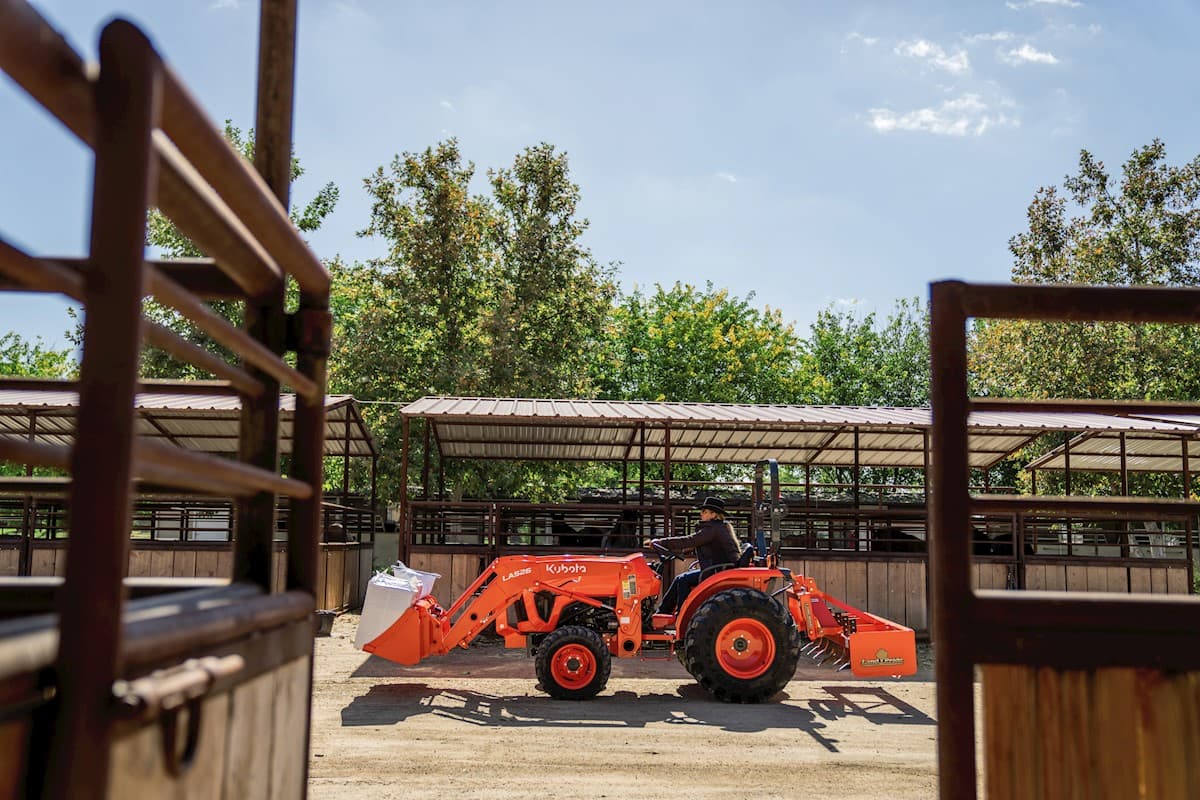 Moan operating compact tractor moving feed through a stable