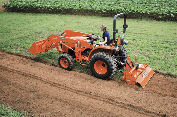 Woman plowing through a plot with compact tractor