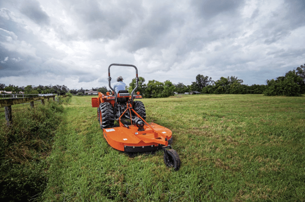 Man mowing lawn with mower attachment