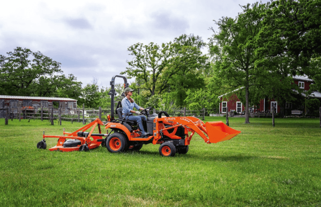 Kubota BX1880 tractor with mower deck and front loader on a rural property